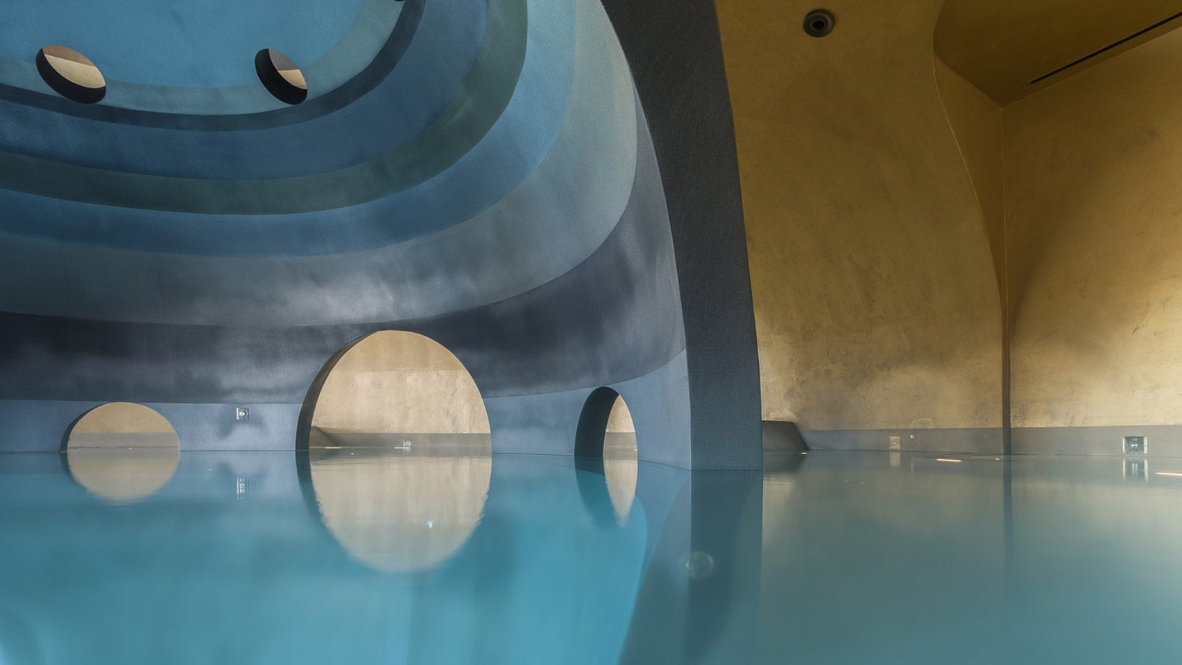 Picture of a minimalist but colourful spa, conveying a galactic impression with tones of blue and gold and circular shapes